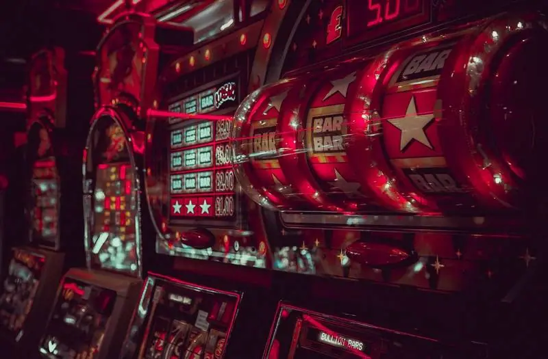 Close-up of the spinning reels of a slot machine with BAR and star symbols under red light